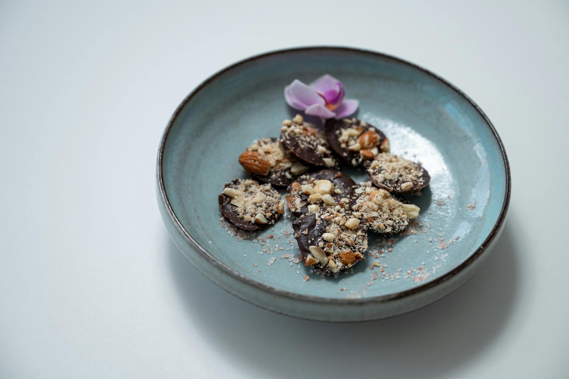 Keto czekoladowy bark z orzechami w misce z dekoracją z orchidei