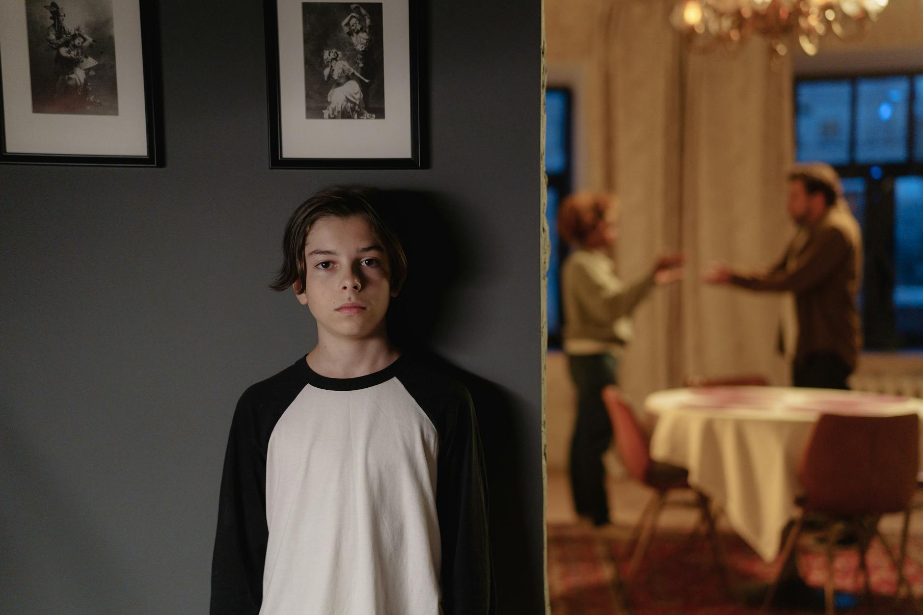 Nastolatek patrzy w dal, podczas gdy rodzice kłócą się w tle