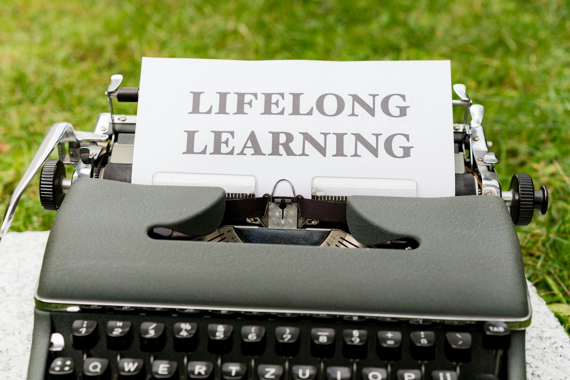 Zbliżenie na maszynę do pisania wystukującą słowa Lifelong Learning outdoors