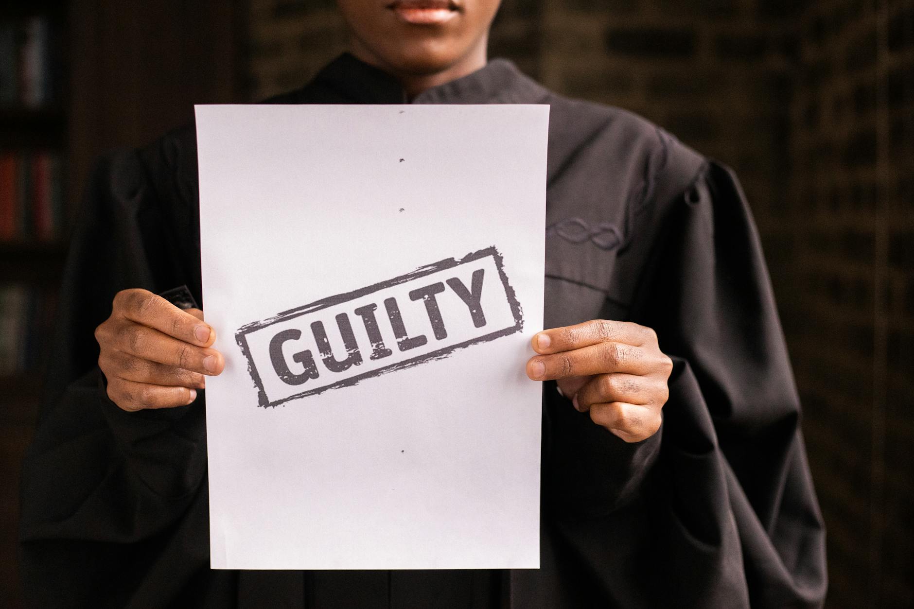 Sędzia na sali sądowej trzyma kartkę z napisem guilty